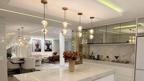 Una cocina moderna con una isla central, luces colgantes y una zona de comedor con sofá y mesa.