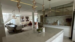 Una cocina moderna con una isla de mármol, luces colgantes y una salpicadera de vidrio.
