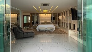 A modern bedroom with a large bed, a sofa, and a television. - The perfect universe | Sonia Mendes House (Brasília)