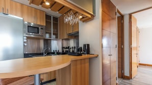 Una cucina moderna con mobili in legno, un frigorifero in acciaio inossidabile, un forno a microonde, una macchina da caffè e un tavolo da pranzo in legno.