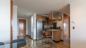 Una cucina moderna con mobili in legno, elettrodomestici in acciaio inossidabile e un tavolo da pranzo in vetro.