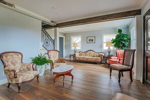 A spacious living room with a wooden floor, a staircase, and a large plant.