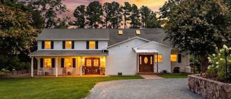 A two-story house with a porch and a garage, surrounded by a well-maintained lawn and trees.
