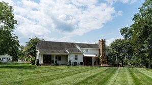 Une maison de plain-pied avec une cheminée en pierre, un porche abrité et une pelouse bien entretenue.