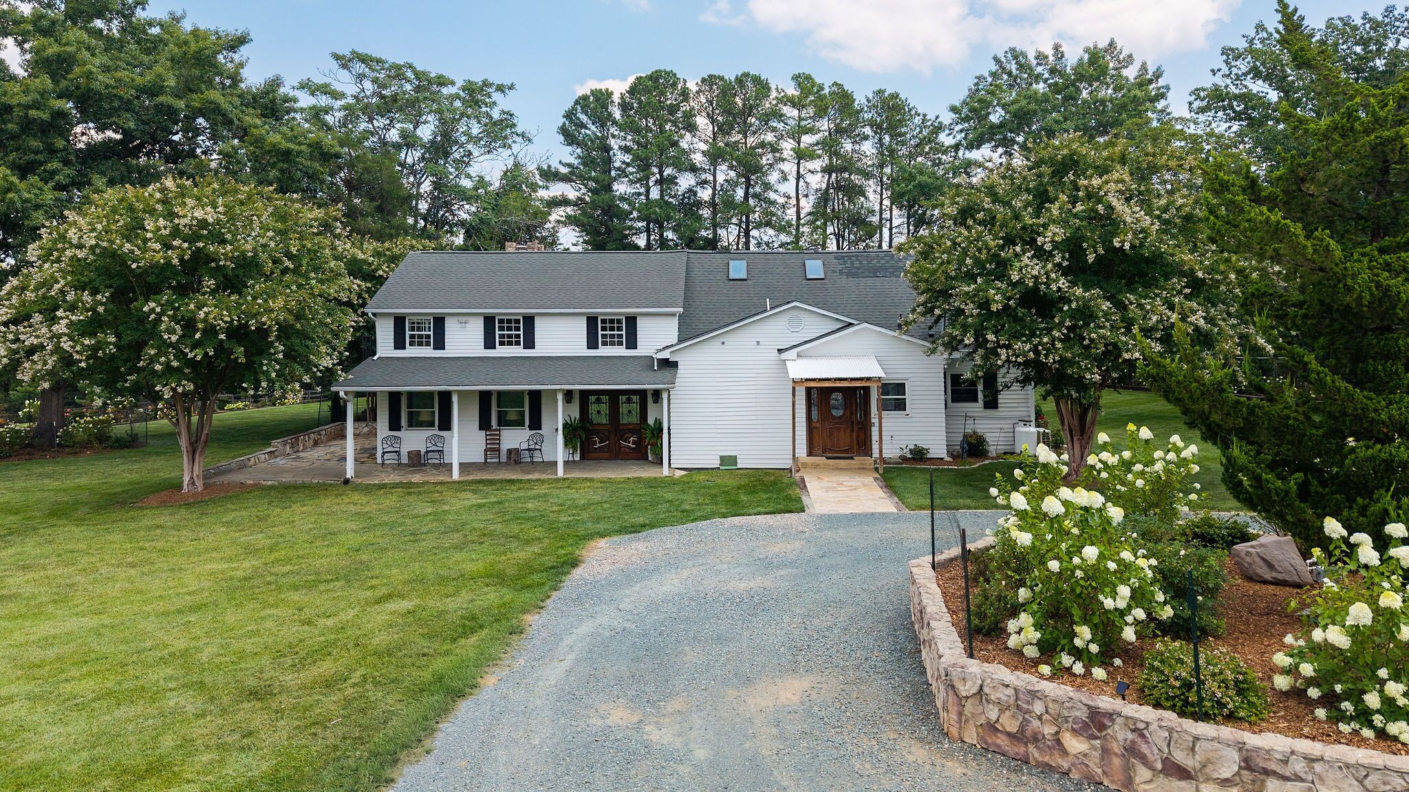 A two-story house with a covered porch and a stone driveway.