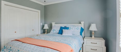 A bedroom with a bed, two bedside tables, a ceiling fan, and a window with blinds.