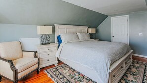 Une chambre à coucher avec un lit, des tables de chevet, une chaise et une porte.