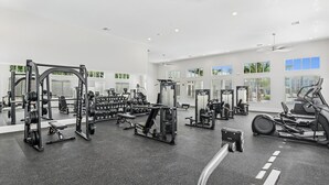 Un gimnasio moderno con diversos equipos de ejercicio, ventanas amplias y un diseño espacioso.
