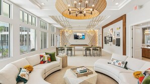 A spacious hotel lobby with a large chandelier, a TV mounted on the wall, and a dining area with a bar. - Landing | Amazing 2BD, Pool, Gym (Palm Bay)