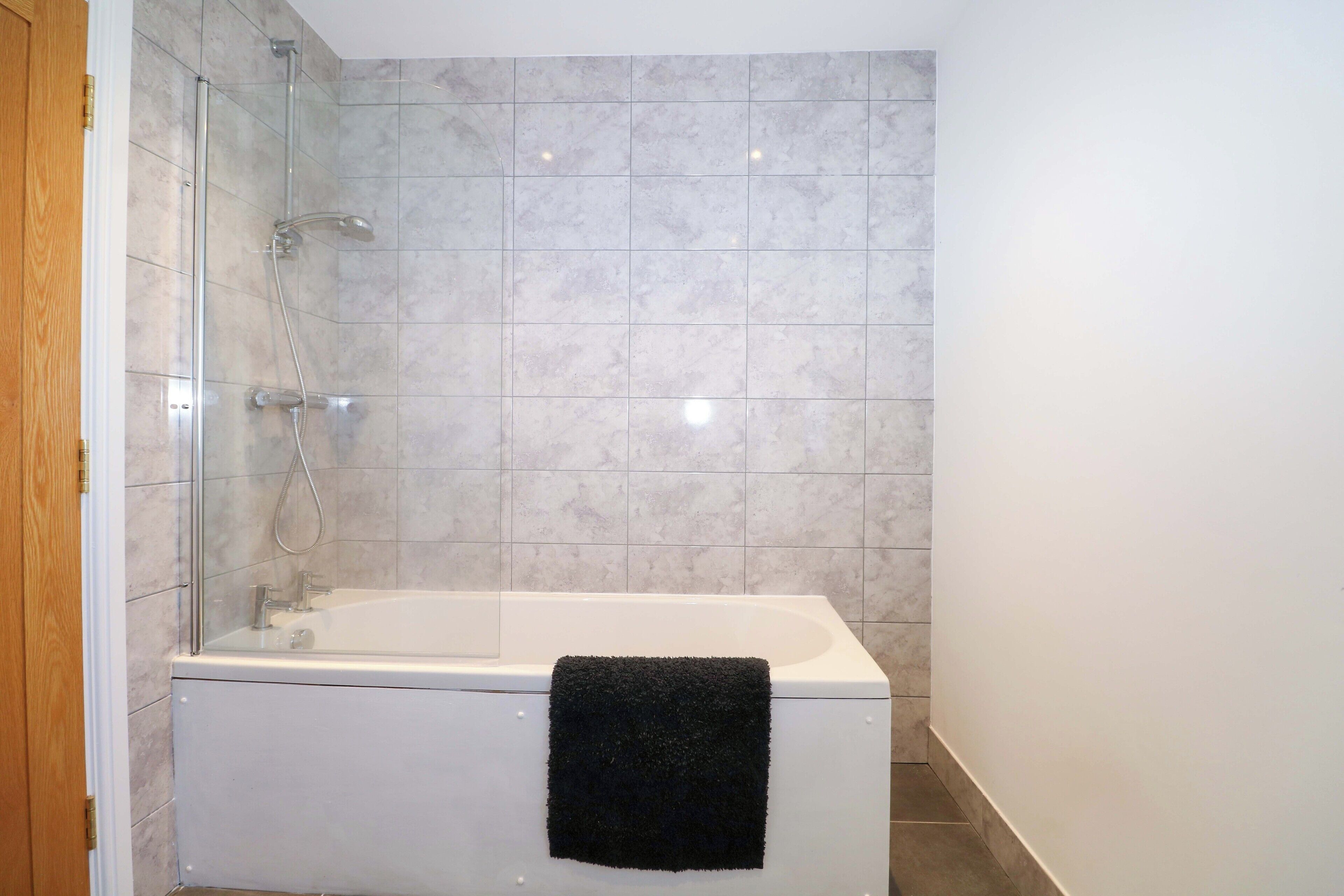 A bathroom with a bathtub, a glass shower enclosure, and tiled walls.