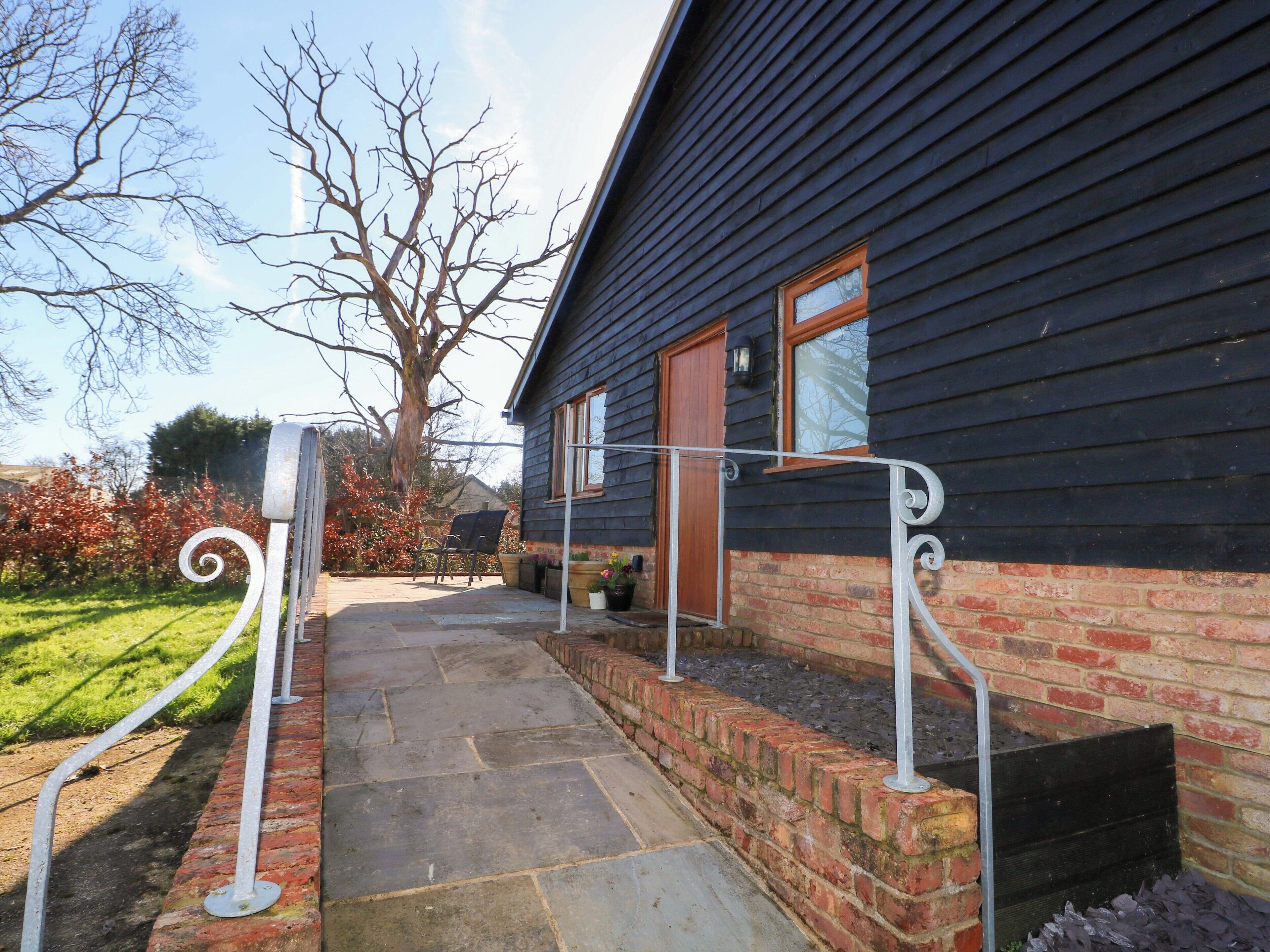A stone pathway leading to a house with a brick foundation and a dark wooden exterior.