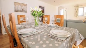 A dining table set with plates, glasses, and cutlery, surrounded by wooden chairs. - Bluebell Cottage (Maidstone)