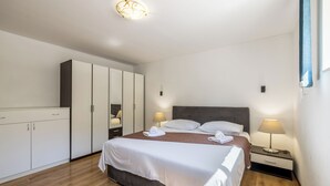 A modern hotel room with a large bed, a wardrobe, a nightstand, and a ceiling light fixture. - Villa sa bazenom u srcu Splita.. (Split)