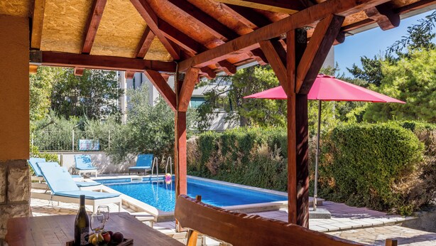 A wooden pergola with a pool table and a bottle of wine. - Villa sa bazenom u srcu Splita.. (Split)