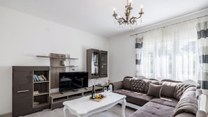 A modern living room with a sectional sofa, a white coffee table, a TV, and a bookshelf. - Villa sa bazenom u srcu Splita.. (Split)