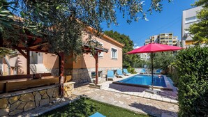 A pool area with stone flooring, a red umbrella, and a pergola with a bench. - Villa sa bazenom u srcu Splita.. (Split)