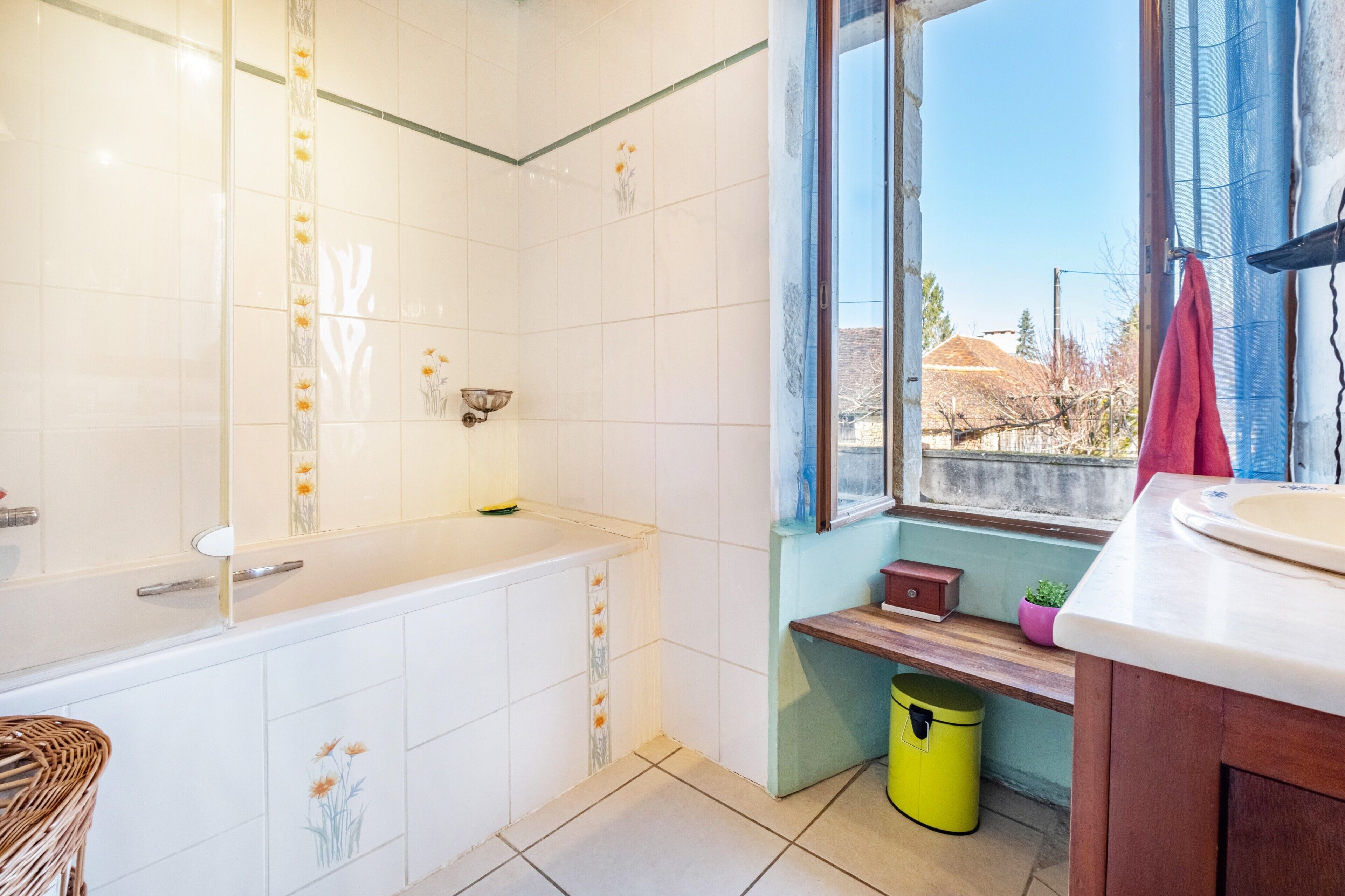 Ein Badezimmer mit Badewanne, einem Fenster mit Ausblick, einem Waschbecken und einem Mülleimer.