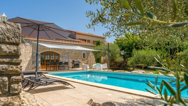 A stone building with a swimming pool, outdoor furniture, and a patio area.