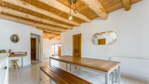 A modern kitchen with wooden beams, a large wooden table, and a bench.