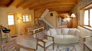 A spacious living area with a wooden ceiling, a white sofa, and a stone wall. - COTTAGE CLOSE TO THE SEA. Pets allowed, ideal for families (lezardrieux)