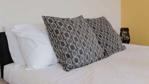 A bed with a white and gray patterned pillow, a plain white pillow, and a black object on the side. - Spacious 4 Bed House With 3 Bathrooms & Parking (Bedford)