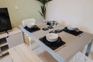 Una mesa de comedor dispuesta con fuentes, copas de vino y cubiertos.