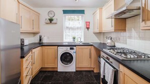A compact kitchen with a washing machine, a stove, and a sink. - Spacious 4 Bed House With 3 Bathrooms & Parking (Bedford)