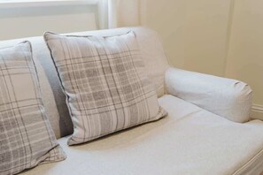 A sofa with a plaid cushion and a plain cushion. - Spacious 4 Bed House With 3 Bathrooms & Parking (Bedford)
