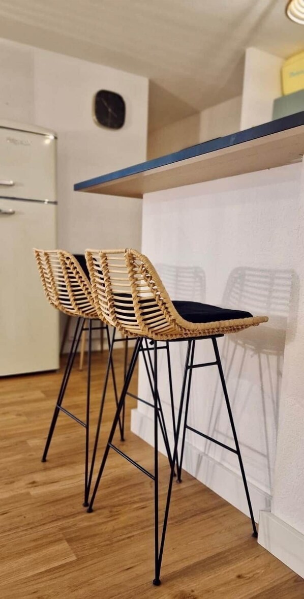 Eine Küche mit zwei Korbstühlen, einem weißen Kühlschrank und einer blauen Arbeitsplatte.