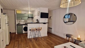 A compact kitchen with a washing machine, a dining area with a table and chairs, and a TV mounted on the wall. - "Marianne "Nice T3 Central, Air-conditioned with Parking (Sète)