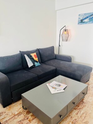 Una sala de estar moderna con un sofá seccional gris, una mesita de centro y una lámpara de pared.