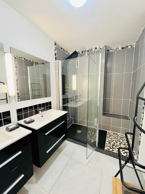 Une salle de bain moderne avec deux lavabos, un espace douche et un miroir.