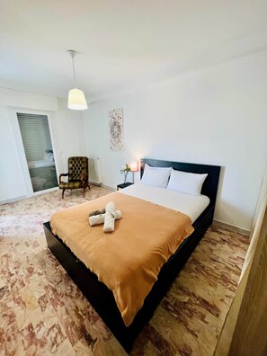 Habitación de hotel ordenada con cama, una silla, una mesita de noche y una lámpara colgante.
