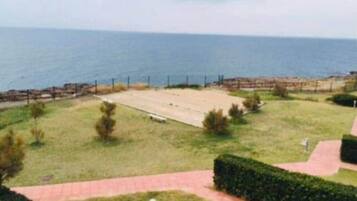 Une vue sur la côte, avec une zone pavée, une clôture et un sentier menant à la mer.