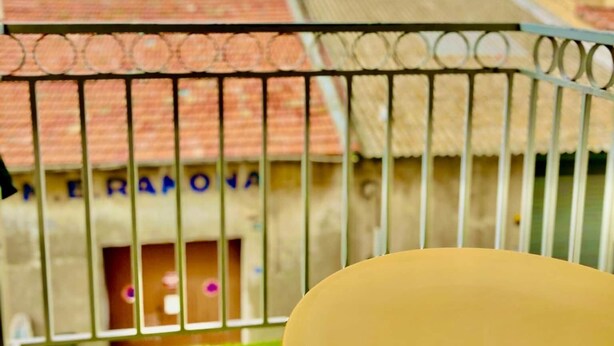 A balcony with a metal railing, a small table, and a view of buildings with red-tiled roofs. - "Ophélia 22" Nice T2 with air conditioning and parking (Sète)