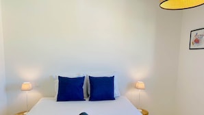 A hotel room with a bed, two pillows, two bedside lamps, and a towel on the bed. - ''Loulou'' T2 modern, bright in the city center, wif parking (Sète)