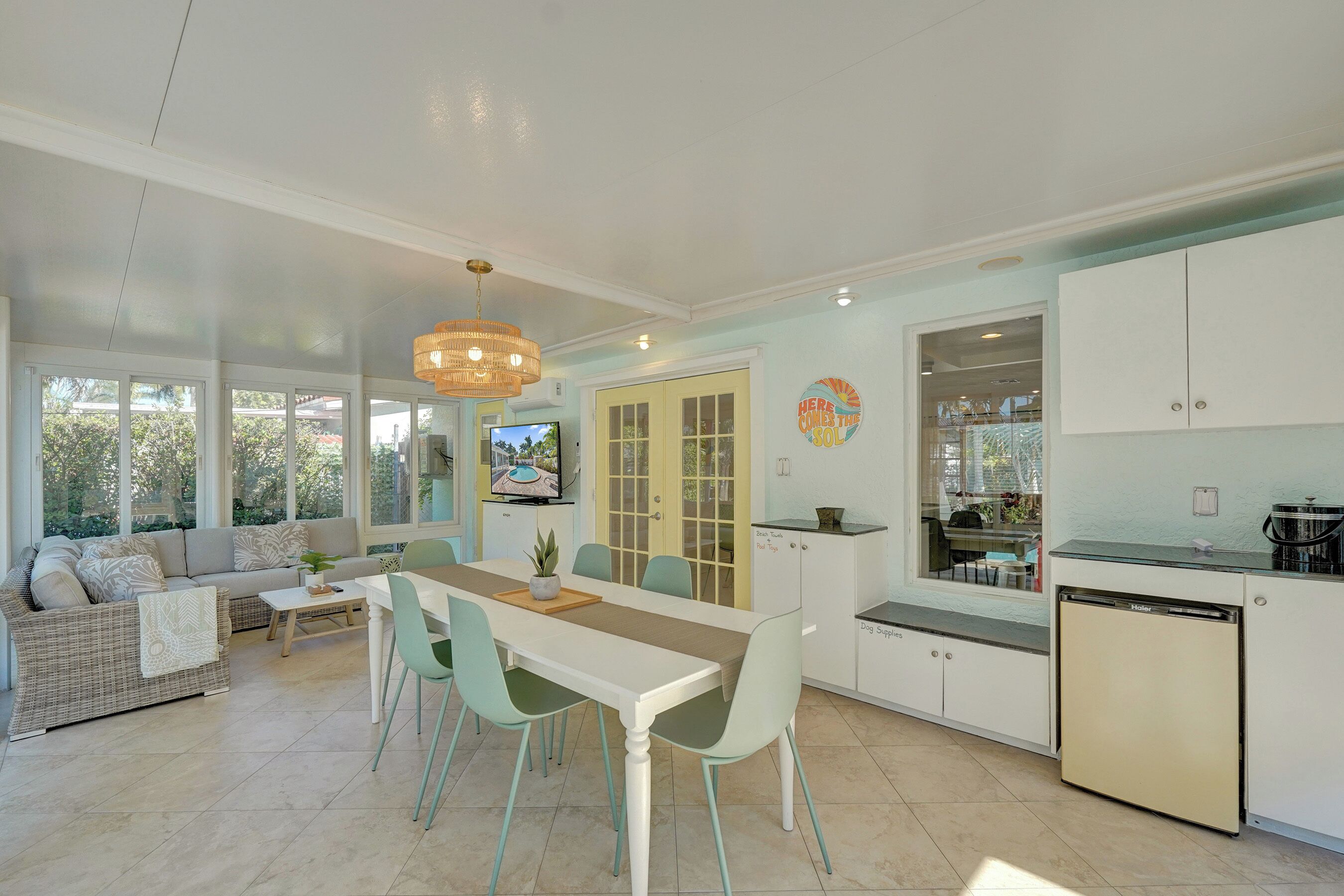 A modern kitchen with a dining area, a sofa, and a television.