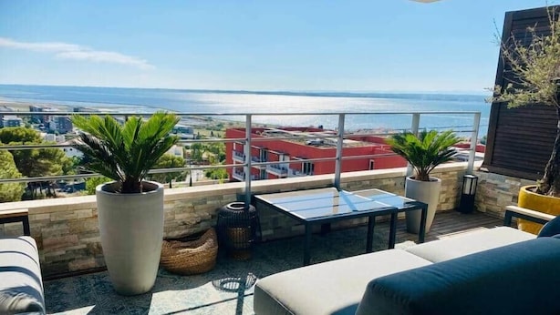 A rooftop terrace with a view of the sea, outdoor furniture, and potted plants. - "Le Soleil" Superb T3 with pond view air-conditioning parking pool (Sète)