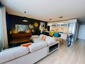 A modern living room with a sectional sofa, a dining area with bar stools, and a kitchen with white cabinets. - "Le Soleil" Superb T3 with pond view air-conditioning parking pool (Sète)