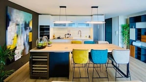 A modern kitchen with a central island, bar stools, pendant lighting, and a large abstract painting on the wall. - "Le Soleil" Superb T3 with pond view air-conditioning parking pool (Sète)