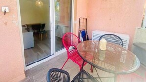 Een glazen tafel met stoelen, een schuifpui en een witte airconditioning.
