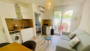 Een ruimtelijk ingerichte leefruimte met kitchenette, eethoek, bank en een klein tafeltje.