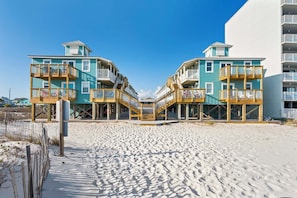 A beachfront hotel with two-story buildings, wooden balconies, and a sandy beach in the foreground. - š Beachfront Complex | Community Pool + Covered Parking | Sunrise Village 105 (Gulf Shores)