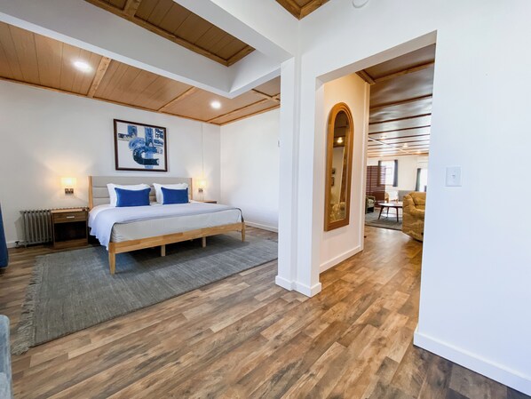 Un dormitorio con una cama de madera, un cuadro grande y un espejo.