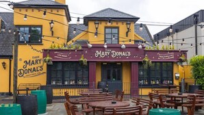 Ein traditionelles Pub namens Tigh Mary Donals mit Außenbereich und einem Schild, das Live-Musik anzeigt.