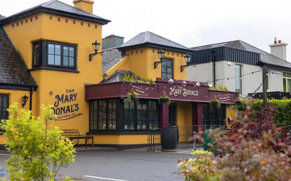 Ein traditionelles Pub mit einer gelben Fassade und einer scharlachroten Markise.