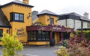 A traditional pub with a yellow facade and a maroon awning. - Tigh Mary Donals Bar & Rooms at Whitegates (Killarney)