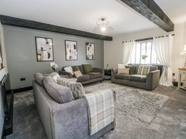 A living room with two sofas, a coffee table, and a rug. There are framed pictures on the wall and a ceiling light fixture.