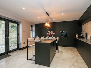 A modern kitchen with a central island, dark cabinetry, and a large window. - 2 Manorhouse Farm (Rochdale)