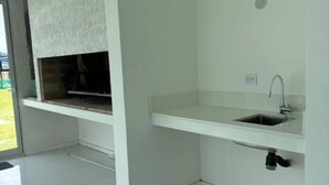 A modern kitchen with a built-in oven, a sink, and a window. - Serena Boutique Potrero Garay (Alta Gracia)